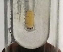 Small sample of pale yellow liquid Fluorine condensed in liquid Nitrogen